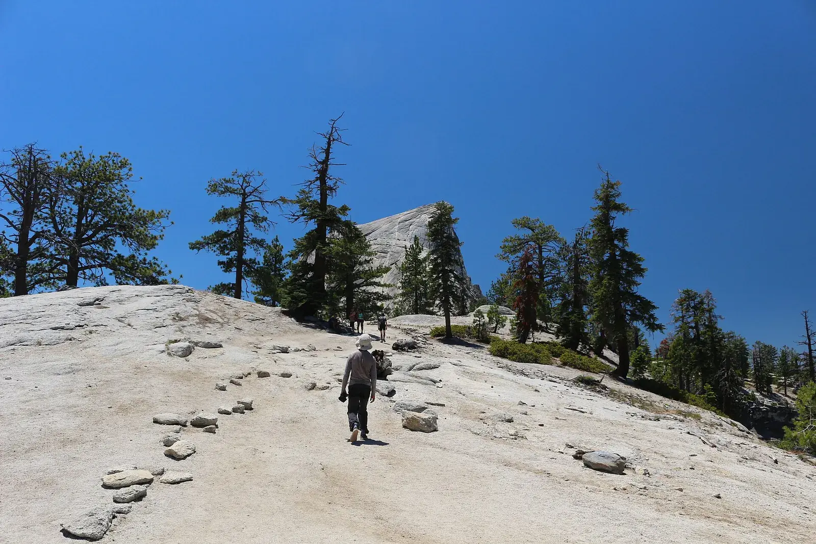 A hiker on the Half Dome trail in Yosemite National Park with Half Dome ahead